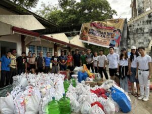 A group of Philippino missionaries stand in front a pile of supplies gathered to help earthquake victims.